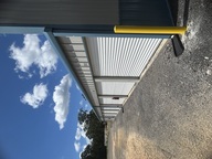Exterior row of storage units with roll-up doors under a blue sky